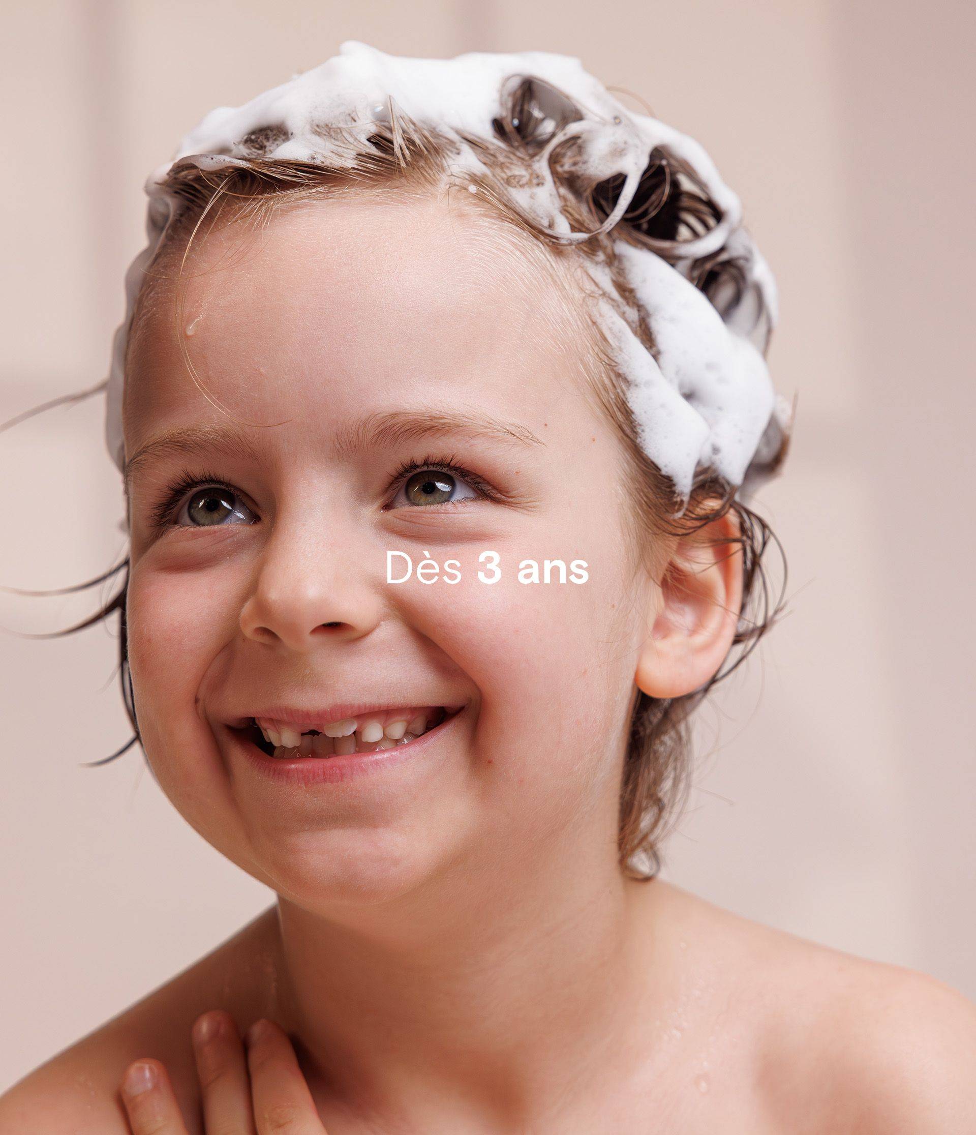 Smiling child with soap suds in hair, labeled "Dès 3 ans" indicating suitable for ages 3 and up.